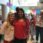 Two ladies dressed nicely in front of crowd of volunteers.